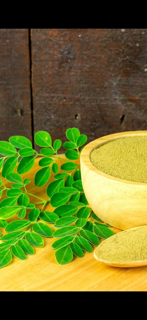 Moringa powder and fresh green leaves in a bowl for health benefits